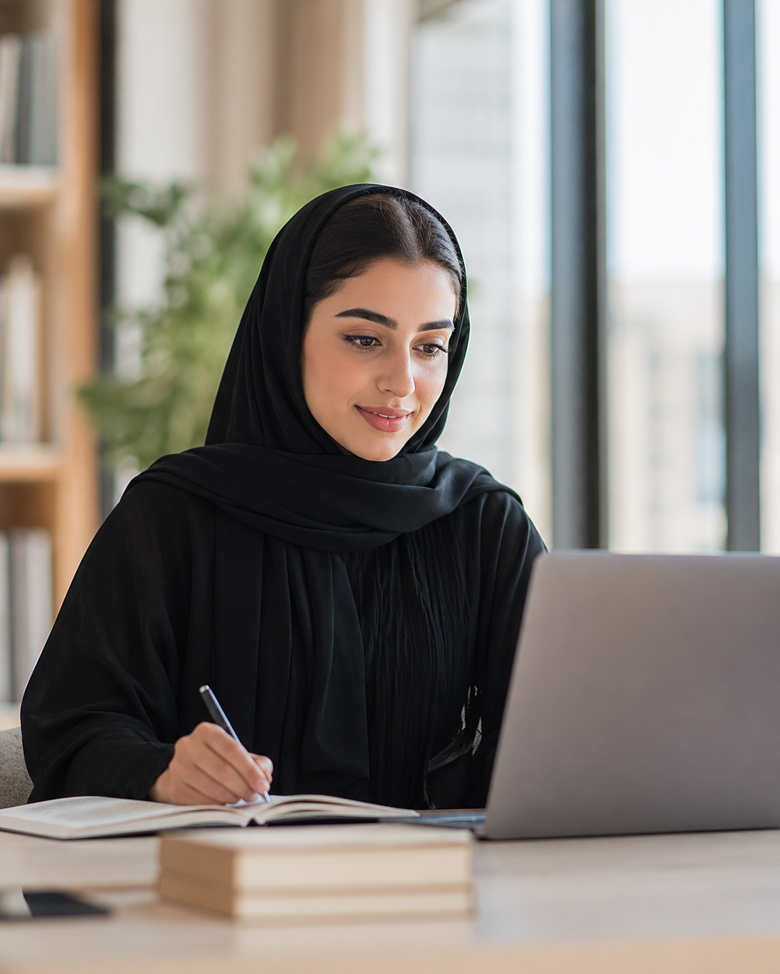 Student taking notes while participating in online learning